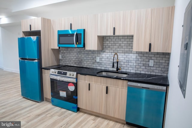 kitchen featuring light brown cabinets, a sink, tasteful backsplash, stainless steel appliances, and light wood-style floors