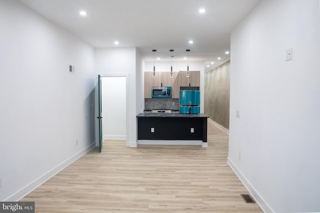 kitchen featuring light wood-type flooring, a center island, stainless steel appliances, and tasteful backsplash