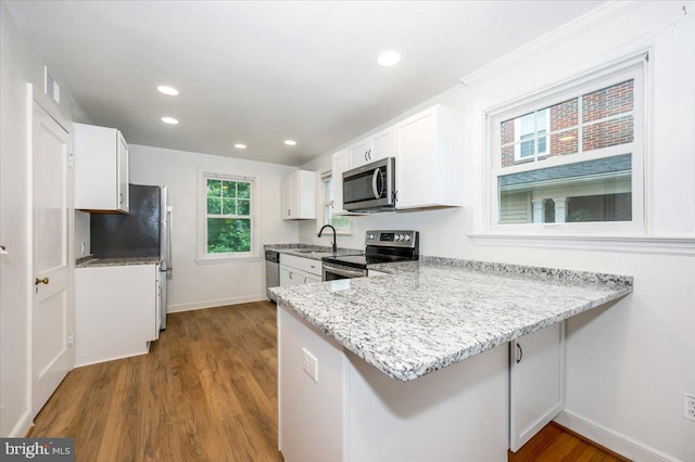 kitchen with kitchen peninsula, stainless steel appliances, white cabinetry, and sink