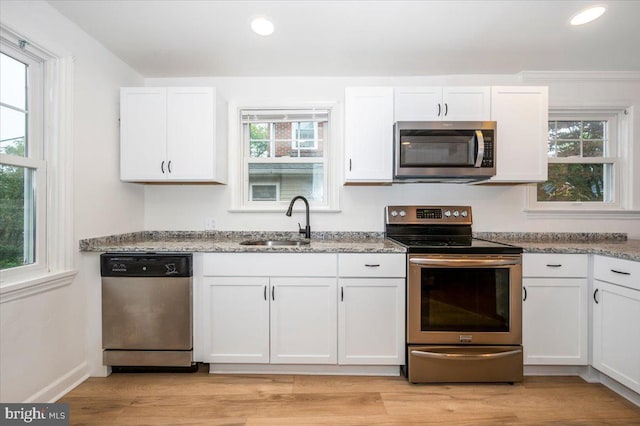 kitchen with stainless steel appliances, white cabinetry, a healthy amount of sunlight, and sink