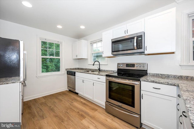 kitchen with white cabinets, light hardwood / wood-style floors, sink, and appliances with stainless steel finishes