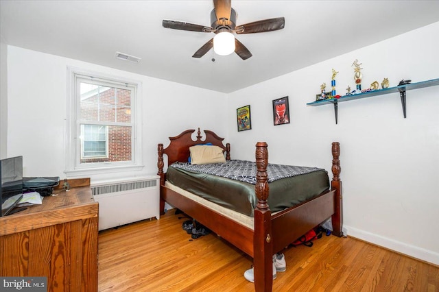 bedroom featuring ceiling fan, radiator heating unit, and light hardwood / wood-style flooring