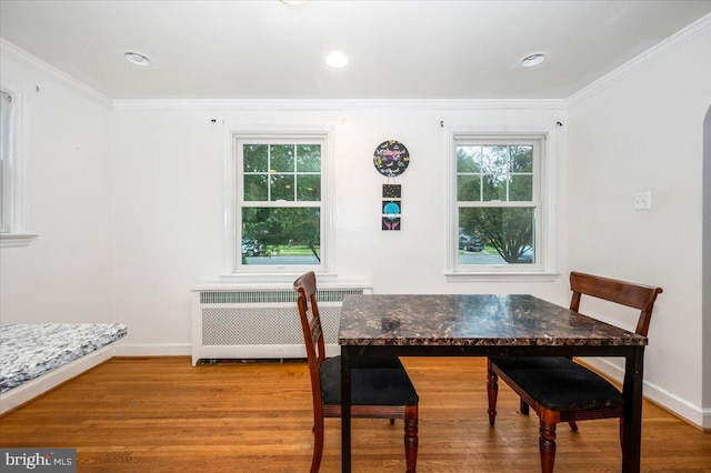 dining room with light hardwood / wood-style flooring, radiator, and crown molding