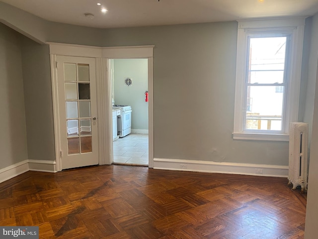 empty room featuring radiator heating unit and dark parquet floors