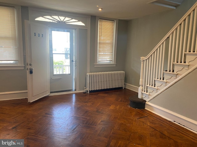 foyer entrance featuring radiator and dark parquet flooring