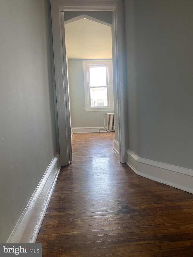 corridor featuring radiator heating unit and dark hardwood / wood-style flooring