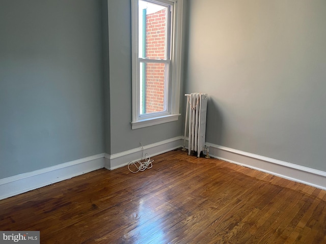 spare room featuring radiator heating unit and dark wood-type flooring