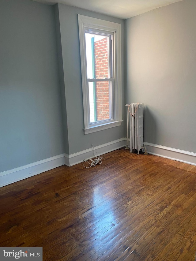 spare room featuring a wealth of natural light, dark hardwood / wood-style floors, and radiator heating unit