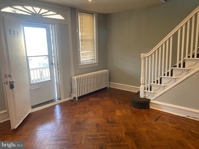 foyer with dark parquet floors and radiator heating unit