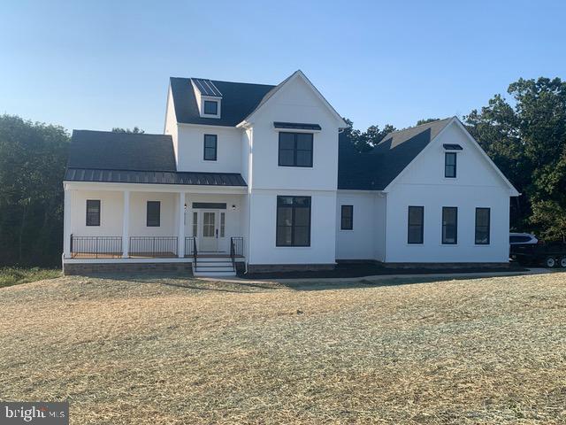 modern farmhouse with covered porch, a front lawn, metal roof, and a standing seam roof