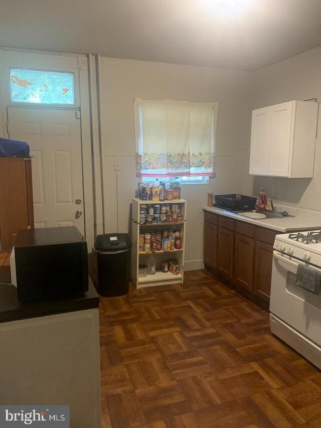 kitchen featuring dark parquet flooring, sink, and white gas range oven