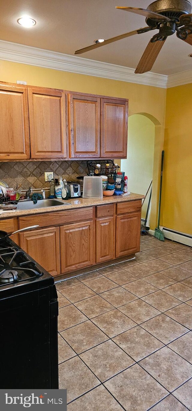 kitchen featuring light tile patterned floors, crown molding, black range oven, decorative backsplash, and ceiling fan