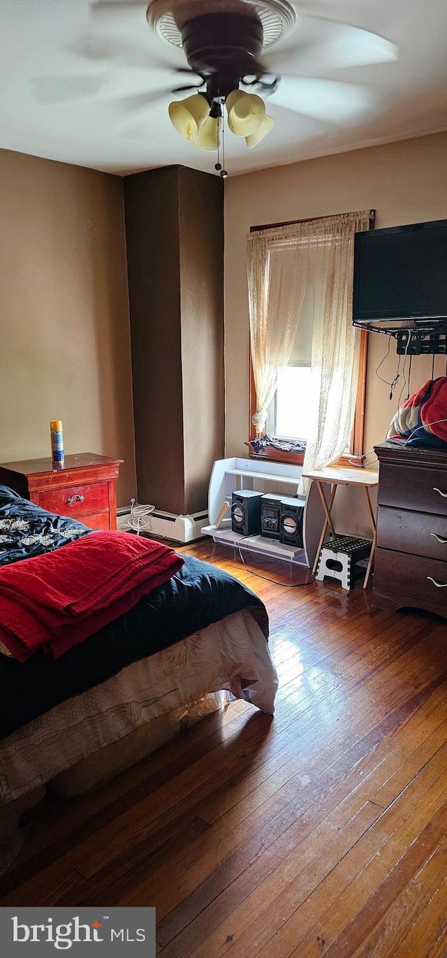 bedroom featuring hardwood / wood-style floors, a ceiling fan, and a baseboard radiator