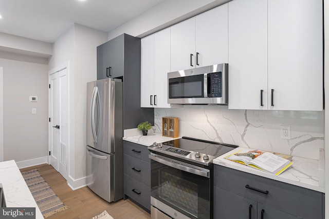 kitchen featuring gray cabinets, stainless steel appliances, white cabinetry, and tasteful backsplash