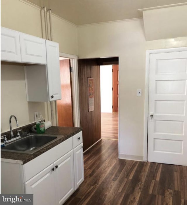 kitchen featuring white cabinets, dark hardwood / wood-style floors, crown molding, and sink