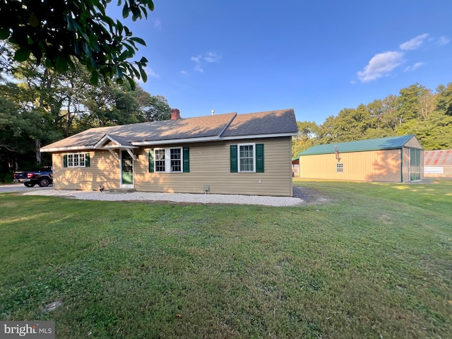 rear view of property featuring a lawn and an outdoor structure