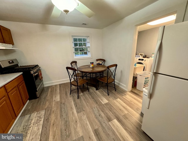 kitchen featuring exhaust hood, white fridge, light wood-type flooring, ceiling fan, and gas stove