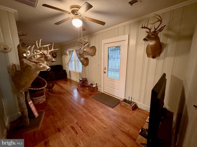 entrance foyer featuring wood-type flooring, ceiling fan, and crown molding