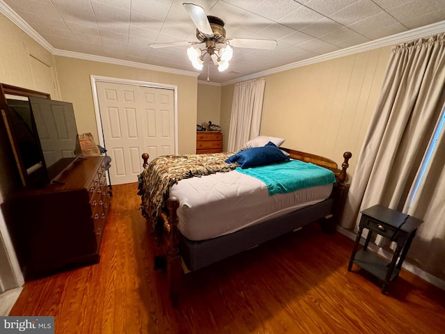 bedroom with crown molding, ceiling fan, dark wood-type flooring, and a closet