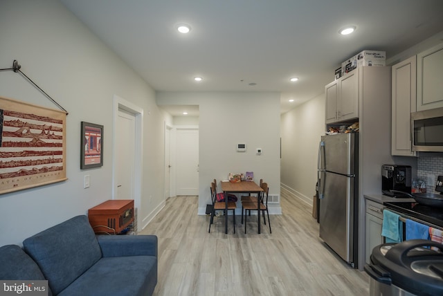 kitchen featuring light hardwood / wood-style flooring, gray cabinetry, appliances with stainless steel finishes, and tasteful backsplash