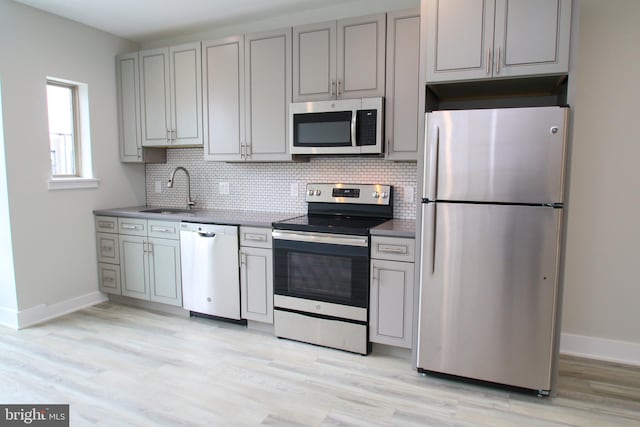 kitchen with light hardwood / wood-style flooring, stainless steel appliances, gray cabinetry, and sink