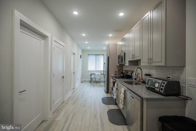 kitchen featuring light hardwood / wood-style floors, tasteful backsplash, gray cabinets, stainless steel appliances, and sink