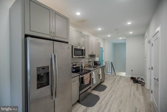 kitchen featuring backsplash, stainless steel appliances, light wood-type flooring, and gray cabinetry