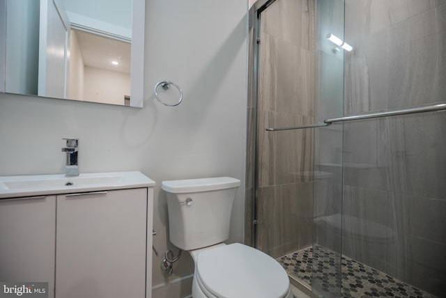 bathroom featuring vanity, a shower with shower door, and toilet