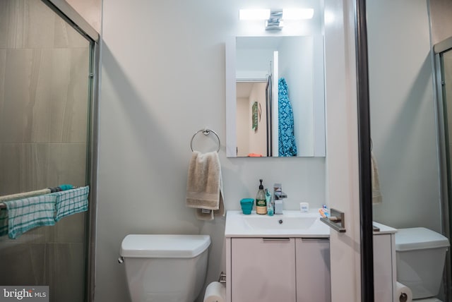 bathroom with a shower with door, vanity, and toilet