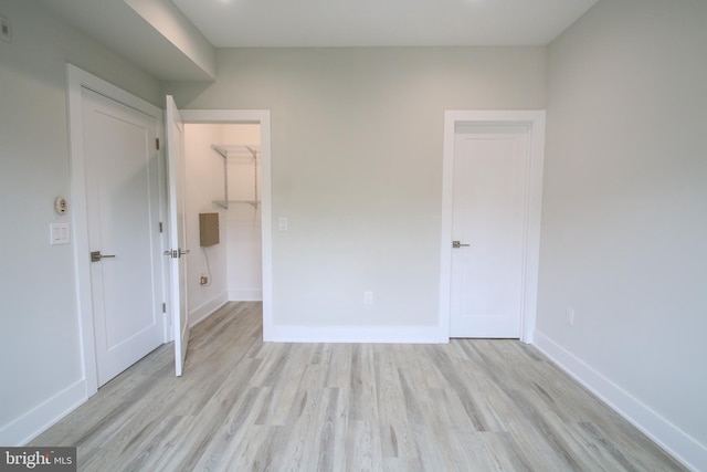 unfurnished bedroom featuring a closet, light hardwood / wood-style floors, and a walk in closet