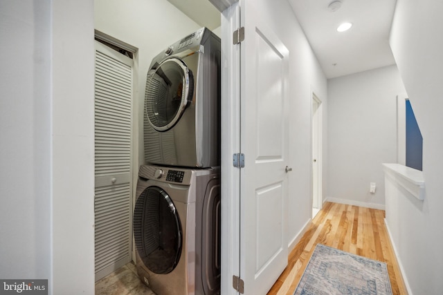 laundry area featuring stacked washer and clothes dryer and light hardwood / wood-style floors