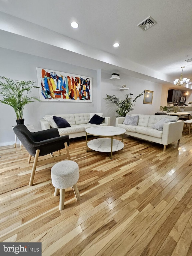 living room with light wood-type flooring and an inviting chandelier