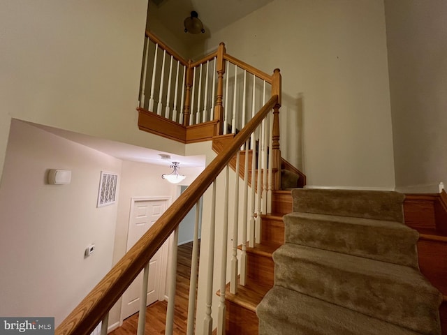 stairs featuring visible vents, wood finished floors, and a towering ceiling