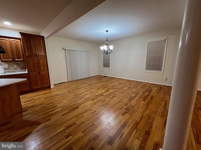 unfurnished dining area featuring light hardwood / wood-style flooring, a chandelier, and beamed ceiling