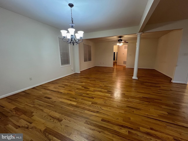 interior space with ceiling fan with notable chandelier, dark hardwood / wood-style floors, and decorative columns