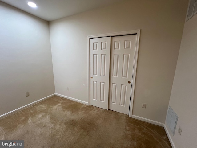 unfurnished bedroom with light carpet and a closet