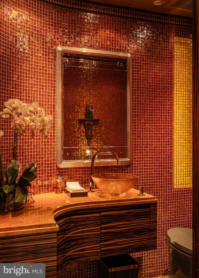 bathroom featuring vanity, toilet, and tile walls