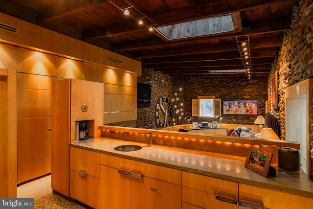 kitchen with sink, a skylight, beamed ceiling, wooden ceiling, and light hardwood / wood-style flooring