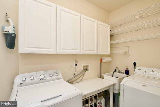 laundry area featuring sink, washing machine and dryer, and cabinets