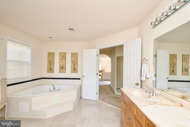 bathroom featuring vanity, tiled tub, and tile patterned flooring