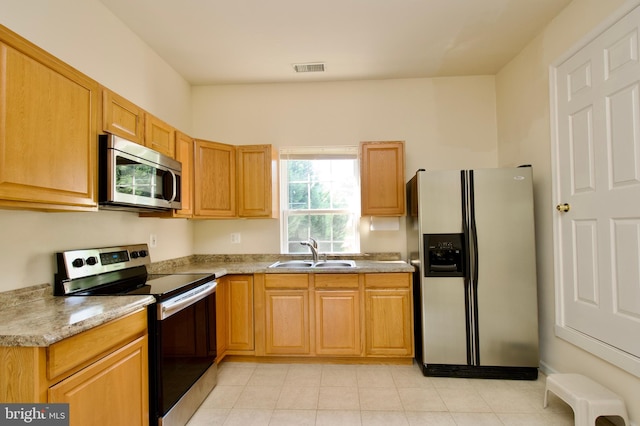 kitchen with light tile patterned flooring, stainless steel appliances, sink, and light stone counters