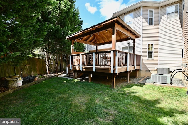 rear view of house featuring a deck, a lawn, and central AC unit