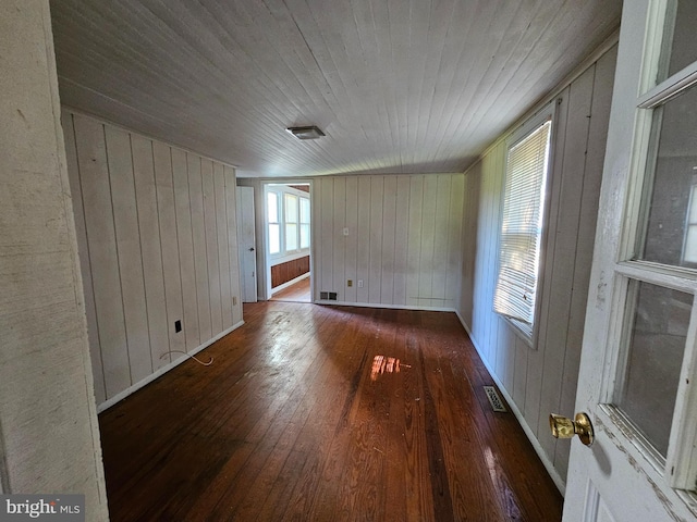 empty room with wooden walls, wooden ceiling, and dark hardwood / wood-style flooring