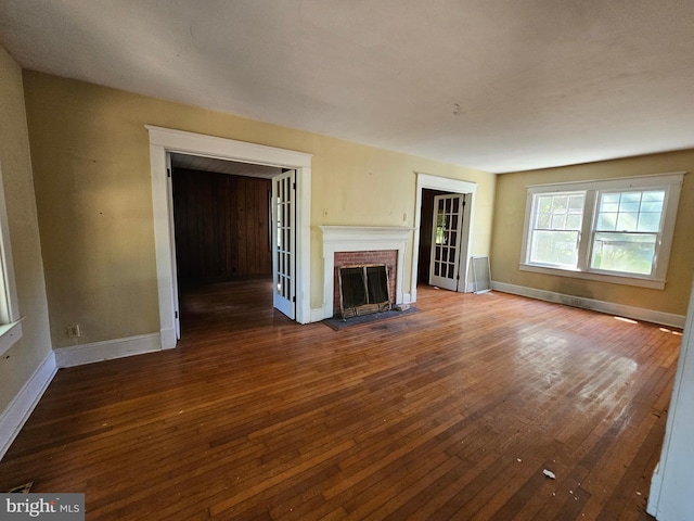 unfurnished living room with dark hardwood / wood-style flooring and a brick fireplace