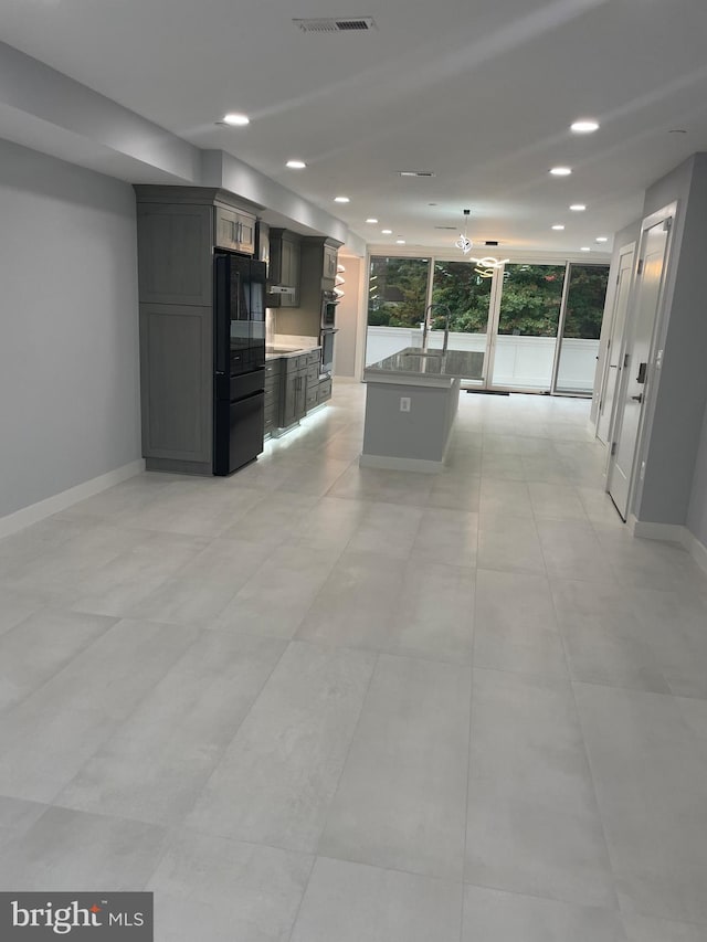 kitchen featuring black fridge, gray cabinetry, a kitchen island, and stainless steel double oven