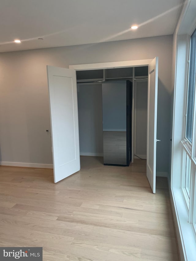 unfurnished bedroom with light wood-type flooring and a closet