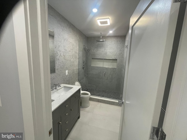 bathroom featuring a shower with shower door, toilet, and vanity