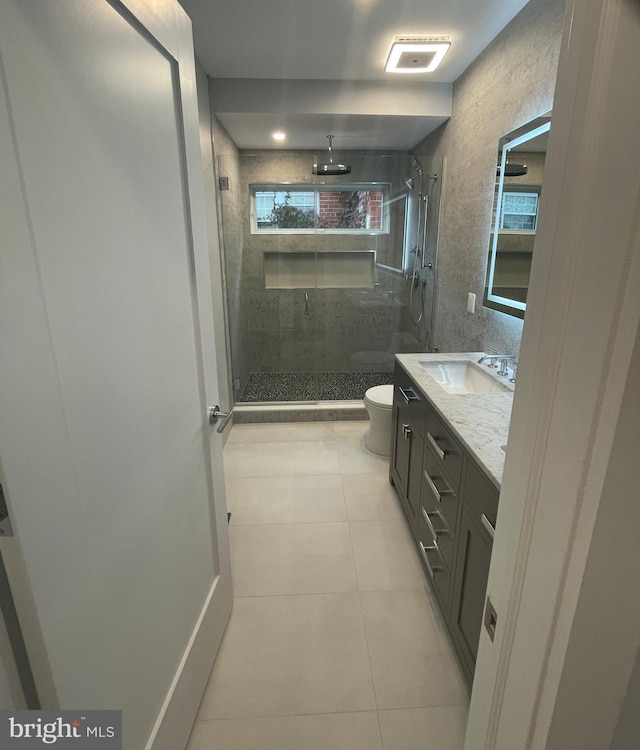 bathroom with a shower with shower door, toilet, vanity, and tile patterned floors