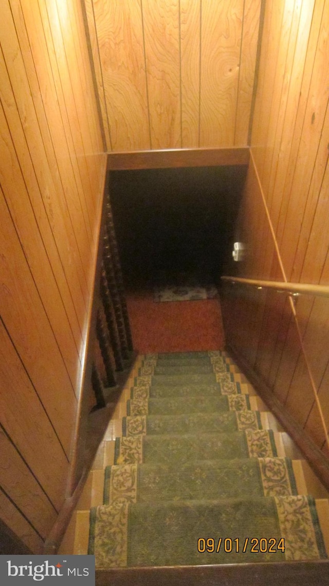 stairway featuring wood walls