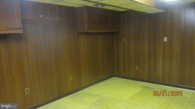 interior space featuring a paneled ceiling and wood walls